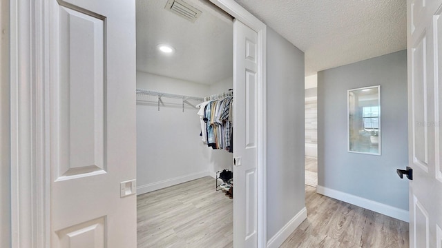 spacious closet with light hardwood / wood-style flooring