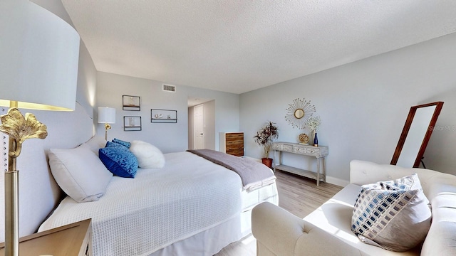 bedroom with a textured ceiling and light wood-type flooring