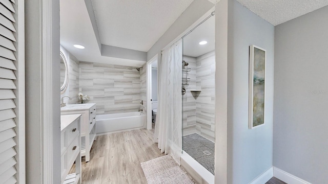 full bathroom featuring hardwood / wood-style flooring, separate shower and tub, vanity, a textured ceiling, and toilet