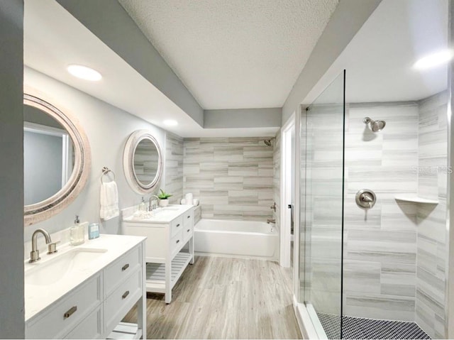 bathroom with vanity, wood-type flooring, independent shower and bath, and a textured ceiling