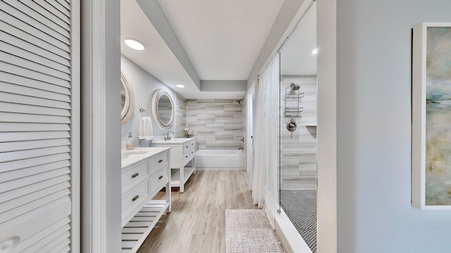 bathroom with vanity, hardwood / wood-style floors, shower with separate bathtub, and a textured ceiling