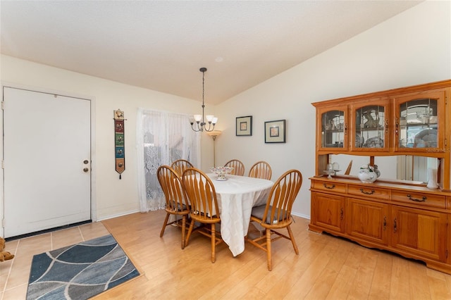 dining area featuring lofted ceiling, light hardwood / wood-style floors, and an inviting chandelier