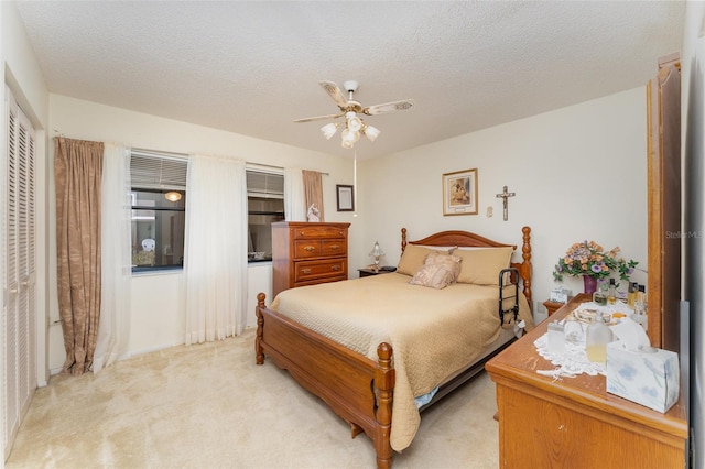 carpeted bedroom featuring ceiling fan and a textured ceiling