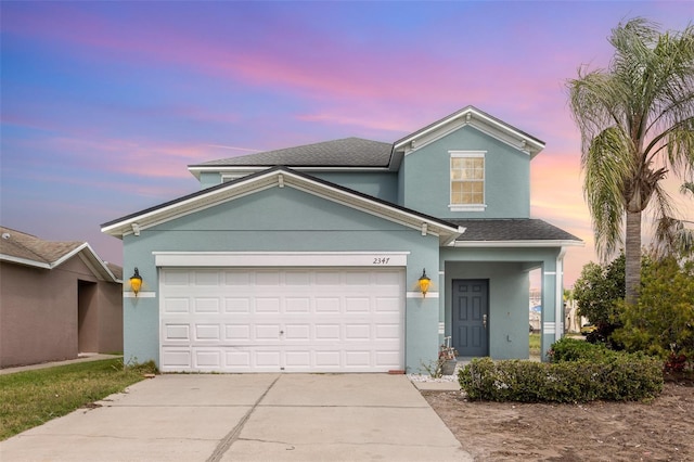 traditional home featuring a garage, driveway, a shingled roof, and stucco siding