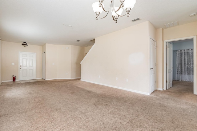 unfurnished living room featuring an inviting chandelier, baseboards, visible vents, and light colored carpet