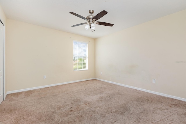 empty room with carpet floors, baseboards, and a ceiling fan