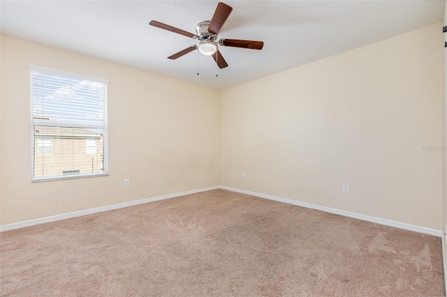 carpeted empty room with baseboards and a ceiling fan