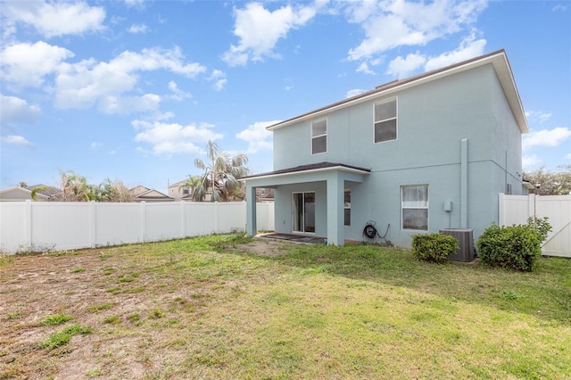 rear view of house with cooling unit, a fenced backyard, a yard, and stucco siding