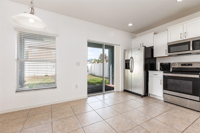 kitchen with decorative light fixtures, stainless steel appliances, white cabinets, light tile patterned flooring, and baseboards