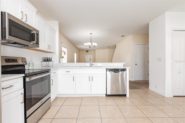 kitchen featuring appliances with stainless steel finishes, light tile patterned flooring, a sink, and a peninsula