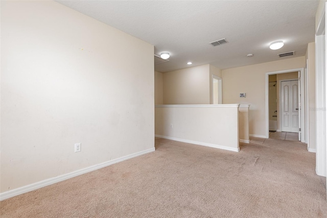 spare room with carpet floors, baseboards, visible vents, and a textured ceiling