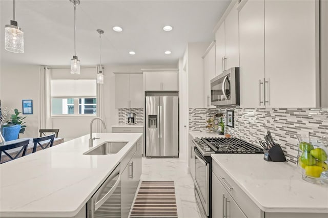 kitchen featuring sink, appliances with stainless steel finishes, hanging light fixtures, an island with sink, and white cabinets