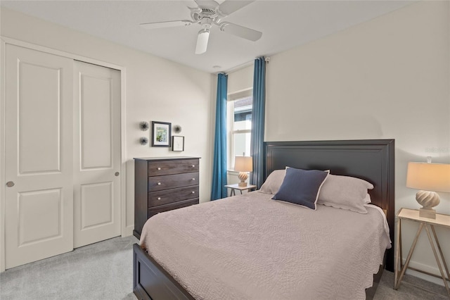 bedroom with ceiling fan, light carpet, and a closet