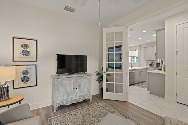 living room featuring wood-type flooring, sink, and ceiling fan