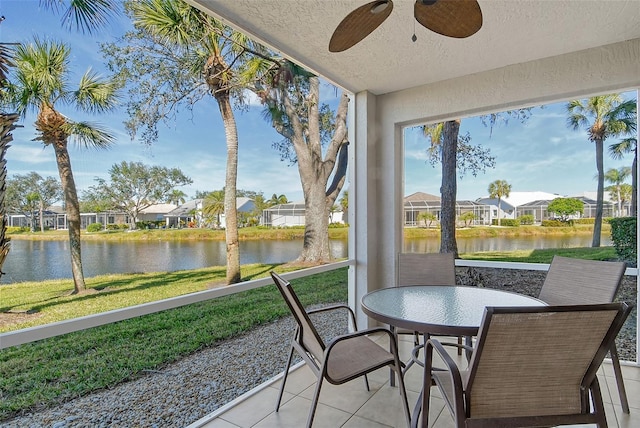 sunroom featuring a water view and ceiling fan