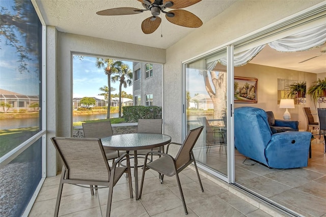 sunroom featuring a wealth of natural light, ceiling fan, and a water view