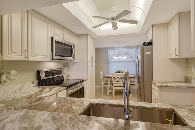 kitchen featuring light stone counters, appliances with stainless steel finishes, sink, and hanging light fixtures