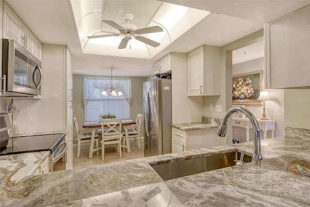 kitchen featuring appliances with stainless steel finishes, decorative light fixtures, sink, white cabinets, and light stone countertops