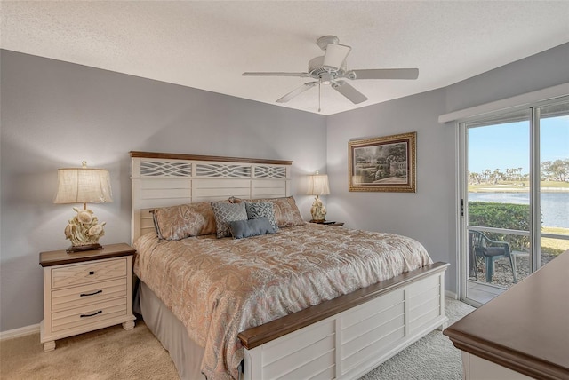 bedroom with access to exterior, light colored carpet, a textured ceiling, and a water view