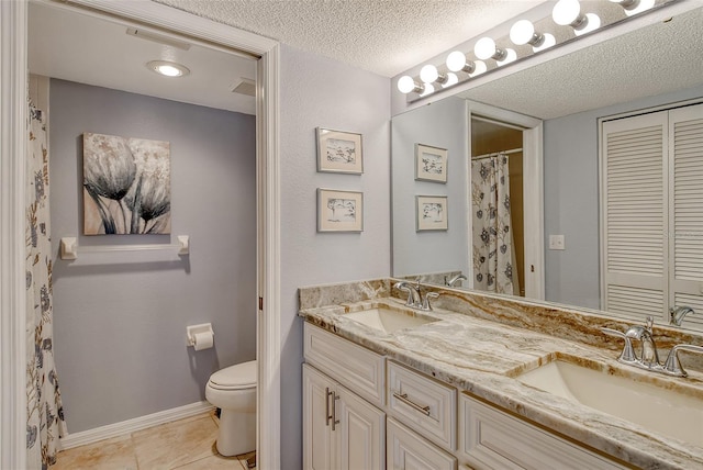 bathroom with tile patterned flooring, vanity, a textured ceiling, and toilet