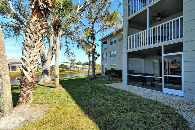 view of yard with a balcony, a water view, and ceiling fan