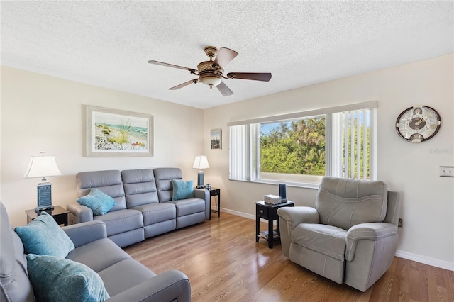 living room with ceiling fan, light hardwood / wood-style flooring, and a textured ceiling