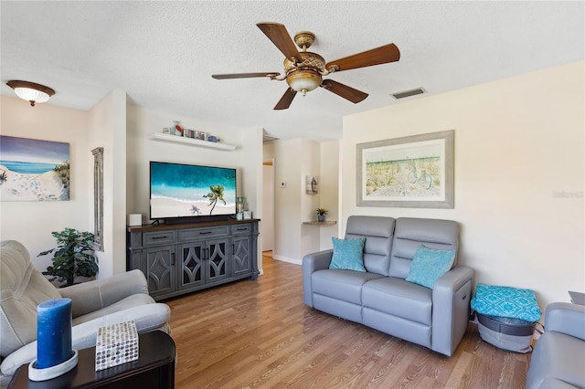 living room with wood-type flooring, ceiling fan, and a textured ceiling