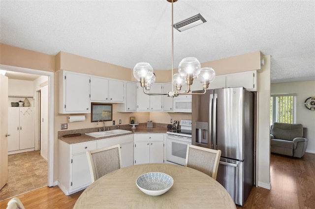 kitchen with stainless steel refrigerator with ice dispenser, sink, white cabinetry, decorative light fixtures, and electric stove