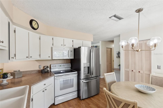 kitchen with hanging light fixtures, sink, white cabinets, and white appliances