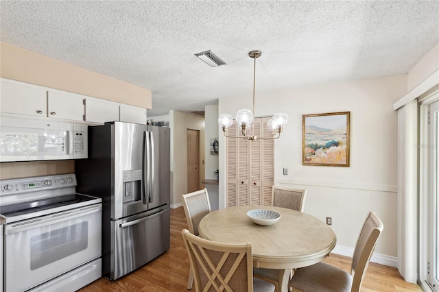 kitchen featuring white cabinetry, hanging light fixtures, white appliances, and light hardwood / wood-style floors