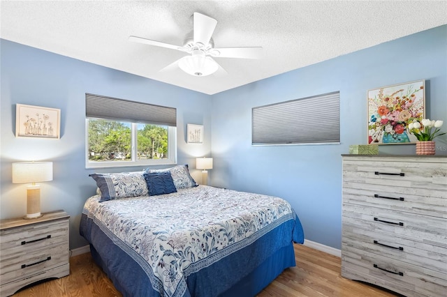 bedroom with hardwood / wood-style flooring, ceiling fan, and a textured ceiling