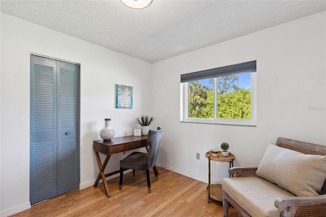 home office with a textured ceiling and light hardwood / wood-style floors