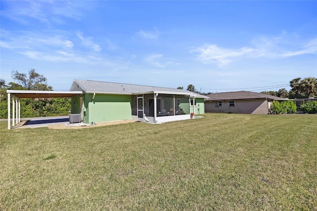 rear view of house featuring central air condition unit, a sunroom, and a lawn