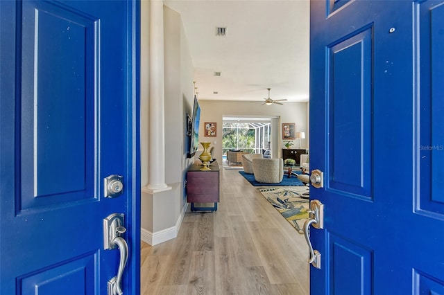 foyer entrance with decorative columns, ceiling fan, and light wood-type flooring