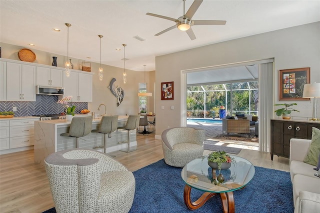 living room with ceiling fan and light hardwood / wood-style flooring