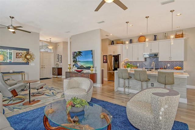 living room with ceiling fan, light hardwood / wood-style floors, and ornate columns