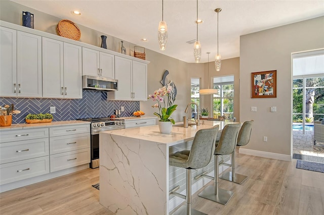 kitchen featuring white cabinetry, appliances with stainless steel finishes, a kitchen breakfast bar, and an island with sink