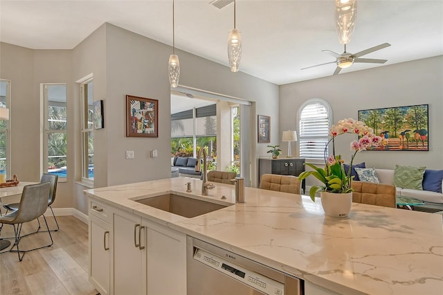 kitchen featuring sink, stainless steel dishwasher, pendant lighting, light stone countertops, and white cabinets