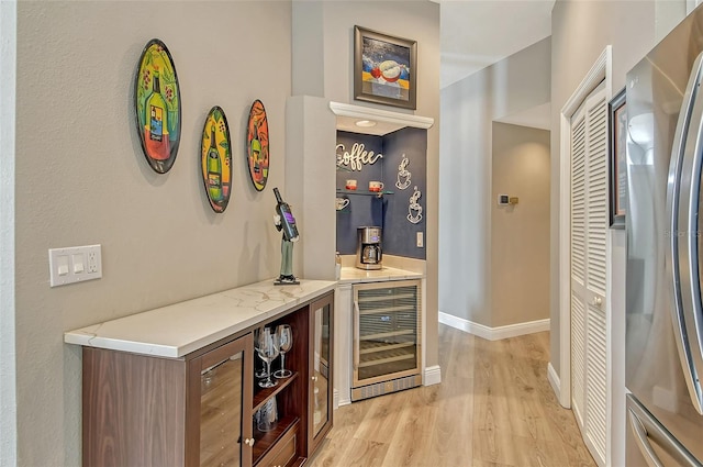 bar featuring beverage cooler, stainless steel fridge, and light wood-type flooring