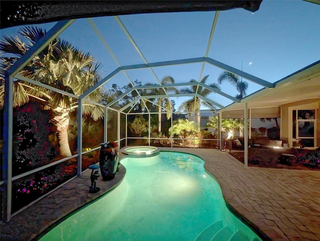 pool at dusk featuring a patio area, an in ground hot tub, and glass enclosure