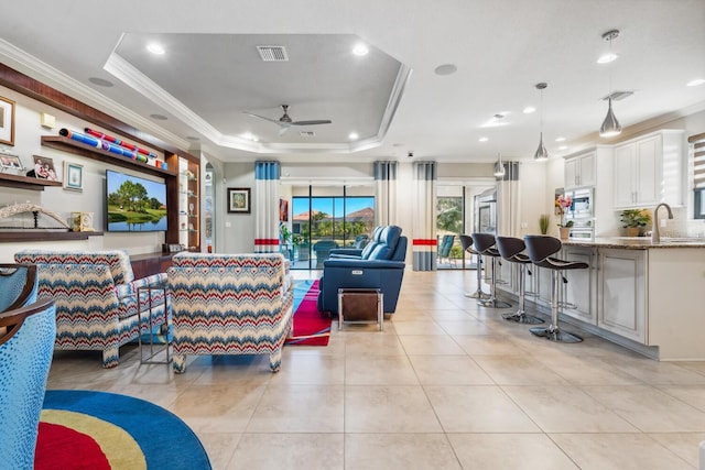 living room featuring ceiling fan, ornamental molding, a raised ceiling, and light tile patterned floors