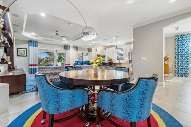 dining area featuring light tile patterned floors, ornamental molding, a raised ceiling, and ceiling fan