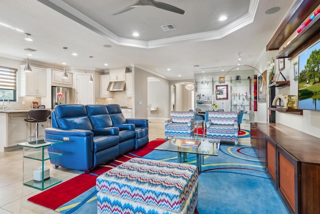 living room featuring ceiling fan, ornamental molding, a raised ceiling, and light tile patterned floors