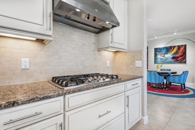 kitchen featuring light tile patterned flooring, ventilation hood, stainless steel gas stovetop, decorative backsplash, and white cabinets