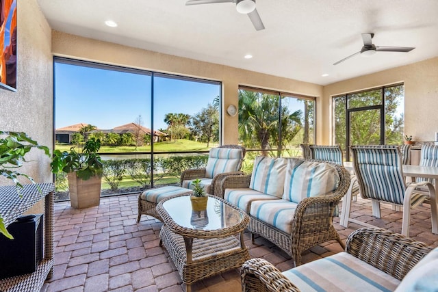 sunroom with a water view and ceiling fan