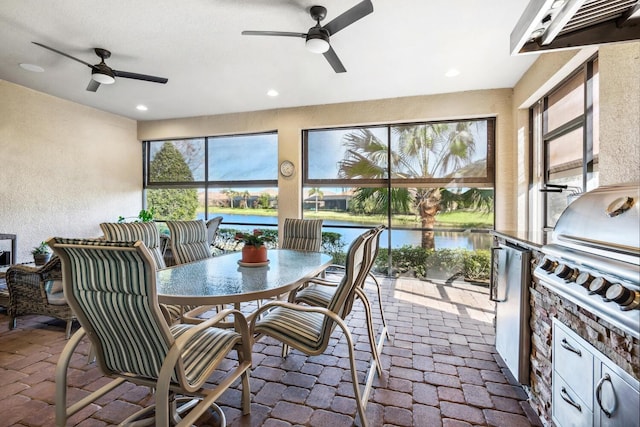 sunroom / solarium with a water view, ceiling fan, and a wealth of natural light