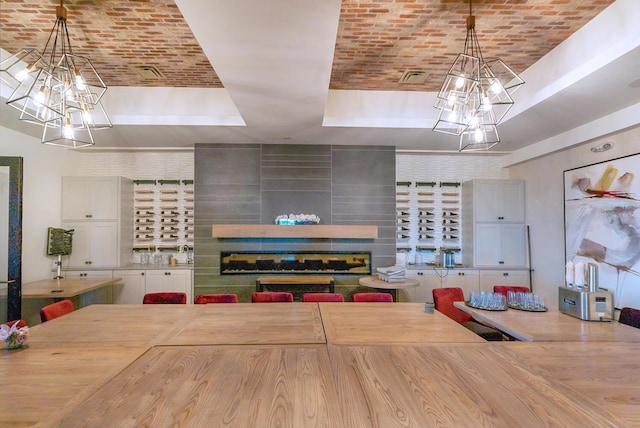 kitchen featuring a raised ceiling, brick ceiling, pendant lighting, and a multi sided fireplace