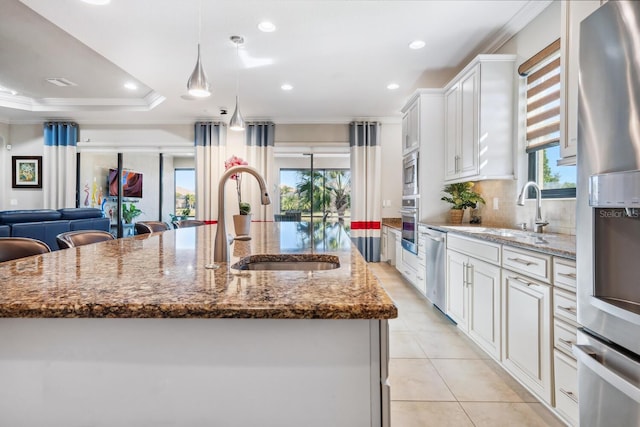 kitchen featuring stainless steel appliances, a spacious island, a sink, and light stone countertops