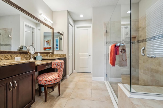 bathroom with a stall shower, tile patterned flooring, baseboards, and vanity