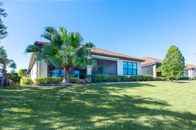 view of front of home with a tiled roof, a front lawn, and stucco siding